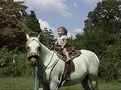Fillette de trois ans apprenant l'équitation, avec un matériel western