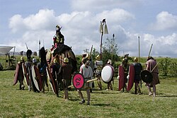 A group of men dressed in clothes and carrying weapons from the 3rd century BC accompanying a medium-sized elephant