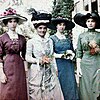 Four women in Edwardian dresses, each a different colour