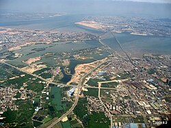 An aerial view of Jimei District (foreground and center), connected by numerous bridges with Xiamen Island's Huli District (in the background right, including Xiamen Gaoqi International Airport).
