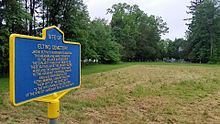 a picture of the marker with a field behind that and, behind that field, the cemtery