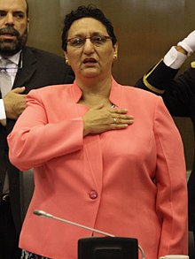Woman in a peach-colored suit taking a pledge with her right hand over her heart