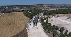 קשת מודיעין בבנייה, ברקע צומת המסילות "כפר דניאל", אוגוסט 2019.