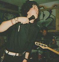 A vocalist and a drummer of a band performing with their band.