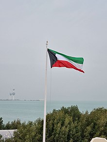 The Flag of Kuwait waving in the Green Island and the Kuwait Towers in the background