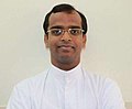 Smiling, bespectacled priest in white tunic