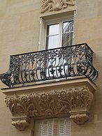 Les balcons en fer forgé avec soubassement sculpté.