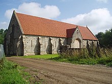 Long stone building with buttressed walls and red tiled roof