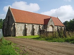 Long stone building with buttressed walls and red tiled roof.