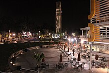 Plaza at night with seats and bell tower in background