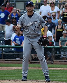 A man in a gray baseball uniform with navy trim and a navy cap