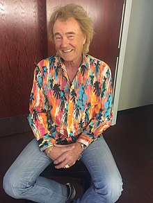 Country music singer Eddy Raven seated on a stool.