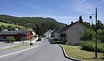 Foto einer Straße, die durch einen Ort führt. An der Straße liegen unter anderem Wohnhäuser.