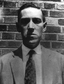 H. P. Lovecraft in front of a brick wall in Brooklyn