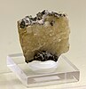 Mineral specimen that is brown in part and cream-colored in part, with a glassy luster, mounted on a plexiglass base