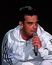 Head and shoulders photograph of Robbie Williams performing live.