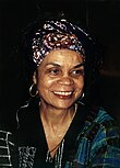 Black woman with head covering, close up, smiling and looking to the right