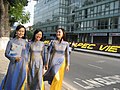 Three girls wearing blue ao dai are leading each other