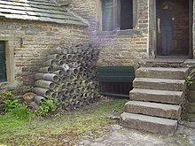 Metal tubes piled against a stone building