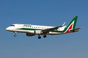 A white, green and red Embraer 175 aircraft in landing configuration.