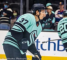 Hockey player skating while wearing a striped blue hockey jersey