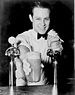 Soda jerk passing an ice cream soda between two soda fountains, New York City, New York, 1936