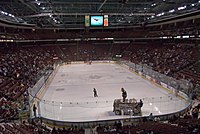 Interior of a ice hockey stadium, with a person dressed as the Utah Grizzlies' mascot riding atop a zamboni on the rink