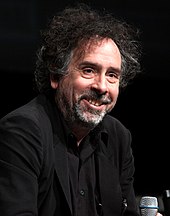 A smiling Tim Burton, dressed in black