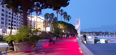 Lumière rouge projetée au sol par des projecteurs le long de la rambarde.