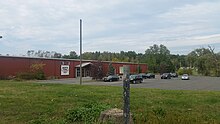 a picture of a post where a marker once was, behind it is a tree stump, another post that once supported something larger