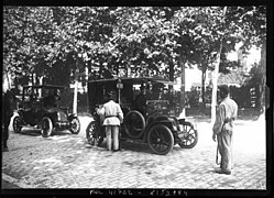 Photo noir et blanc d'une voiture arrêtée par des gendarmes dans une rue arborée.