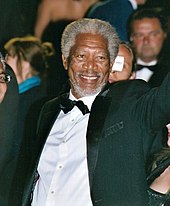 Morgan Freeman smiling and waving, facing right