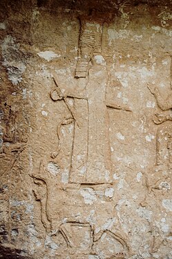 Représentation du dieu Assur sur les reliefs de Maltai, sur un dragont-serpent mušhuššu et tenant l'anneau et le bâton, insignes de la royauté, dirigeant une procession de divinités, face au roi (probablement Sennachérib), placé à gauche de l'image.