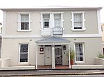 Semi-detached double storey dwelling probably Victorianised. Full hipped corrugated iron roof; plaster quoining around upper floor openings; and a plaster band at position of removed verandah; sash windows of later Victorian type, lower floor probably mo Type of site: House Current use: House.