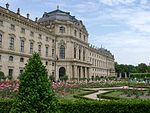 A large Baroque palace with a flower garden in front