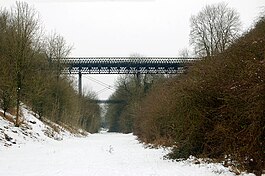 A lattice-girder wrought iron bridge, spanning a snow-covered railway cutting