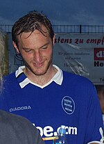 A man wearing a blue top with a white collar.