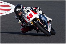 Juan Guevara durante treinamento para a MotoGP em Silverstone em 31 de Agosto de 2013, ele dirige uma moto branca utilizando um macacão branco e capacete durante uma curva a direita.