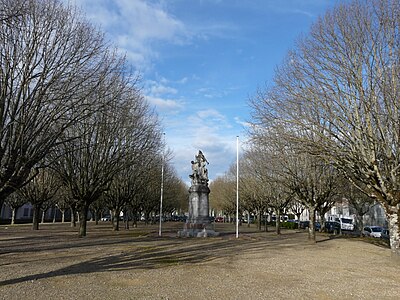 2 rows of trees aligned on either side of a wide driveway, with the war memorial in the center.