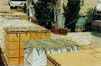 Different types of kosher s'chach serve as roofs for sukkot: woven bamboo mats (far left and right); palm leaves (center)