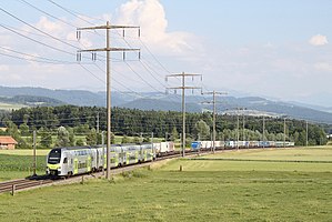 Silver double-decker train surrounded by fields