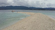 The end of a long sandy cay, with a seaplane parked nearby