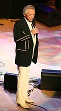 Country music singer Mel Tillis is performing on a stage.
