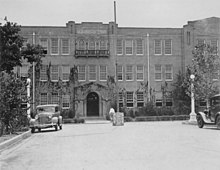 Distant view of a building with a street and cars in the foreground