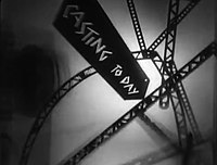 A series of slanted and curving girders representing an abstract city landscape are set in front of a hazy white backdrop. A slanted black sign appears in the foreground with the words "CASTING TODAY" written in jagged white text.