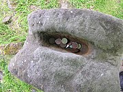 Photo of the top of the Janus statue, with an indentation filled with coins