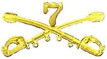 A computer generated reproduction of the insignia of the Union Army 7th Regiment of Cavalry. The insignia is displayed in gold and consists of two sheafed swords crossing over each other at a 45-degree angle pointing upwards with a Roman numeral 7
