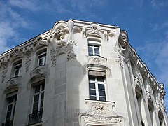 Photographie de la façade supérieure d'un immeuble de tuffeau orné de bustes de femmes.