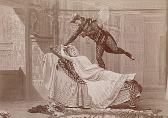 man dressed as a giant fly hovering over a reclining young woman