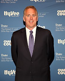 Chuck Long in a suit, smiling, shown from about the waist up and posing for pictures.